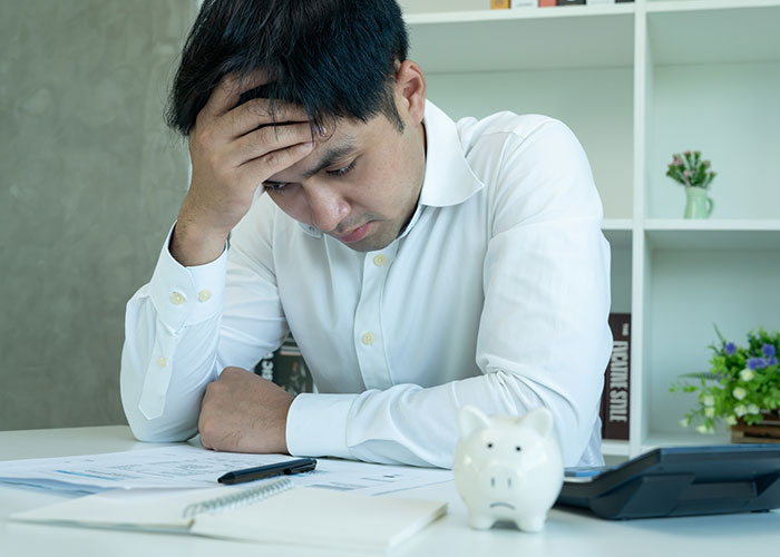 Person stressed with bills representing overwhelming debt and financial pressure